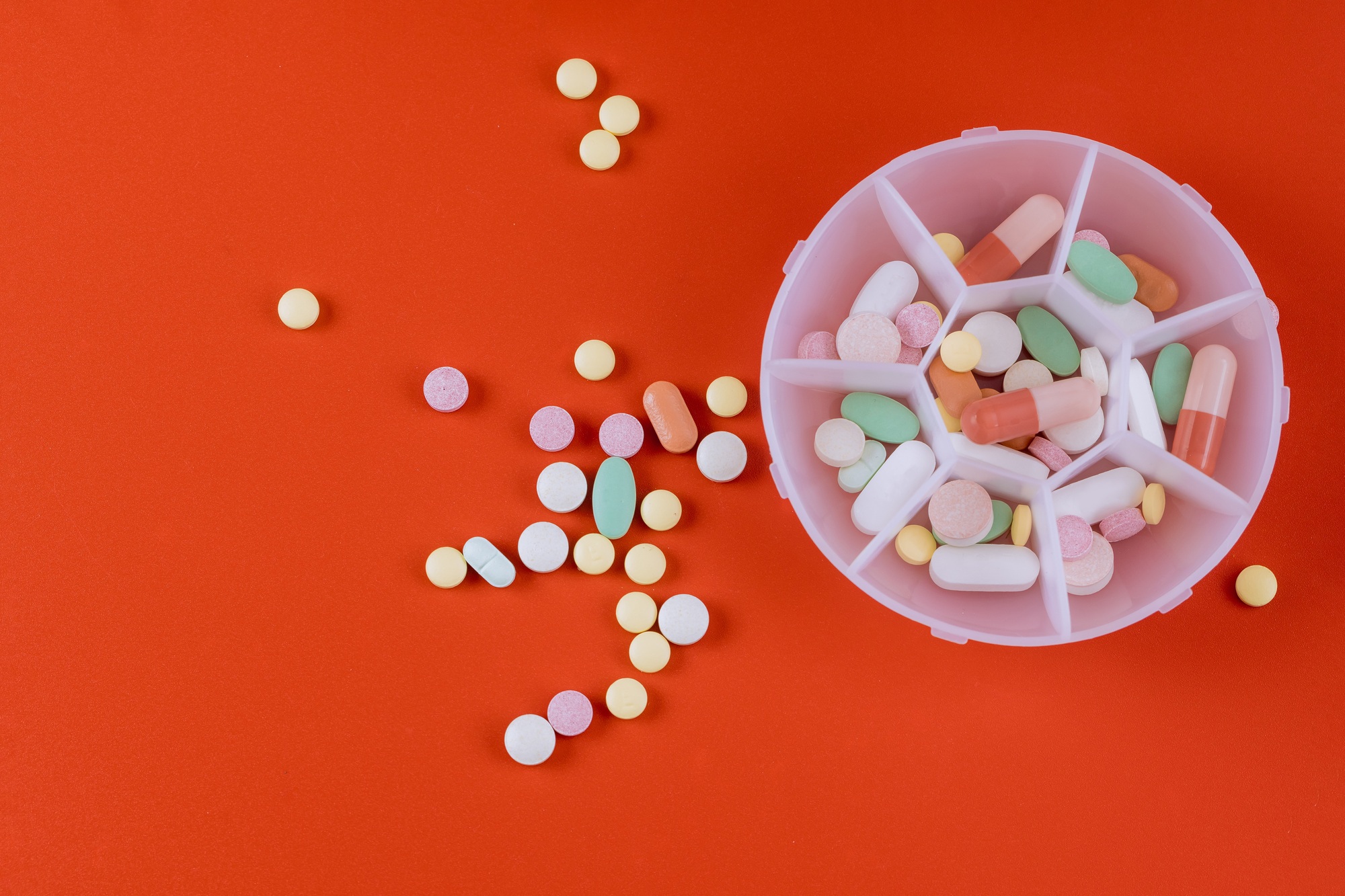 Colorful pills tablets antibiotic on red background